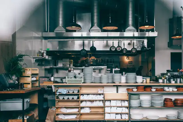 Cozinha de restaurante com pilhas de pratos e utensílios na bancada