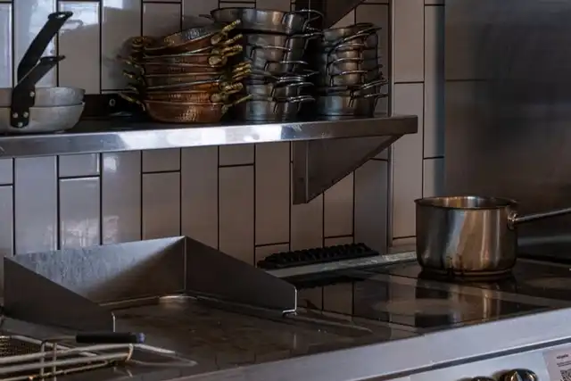 Cozinha industrial com fogão e panelas de inox