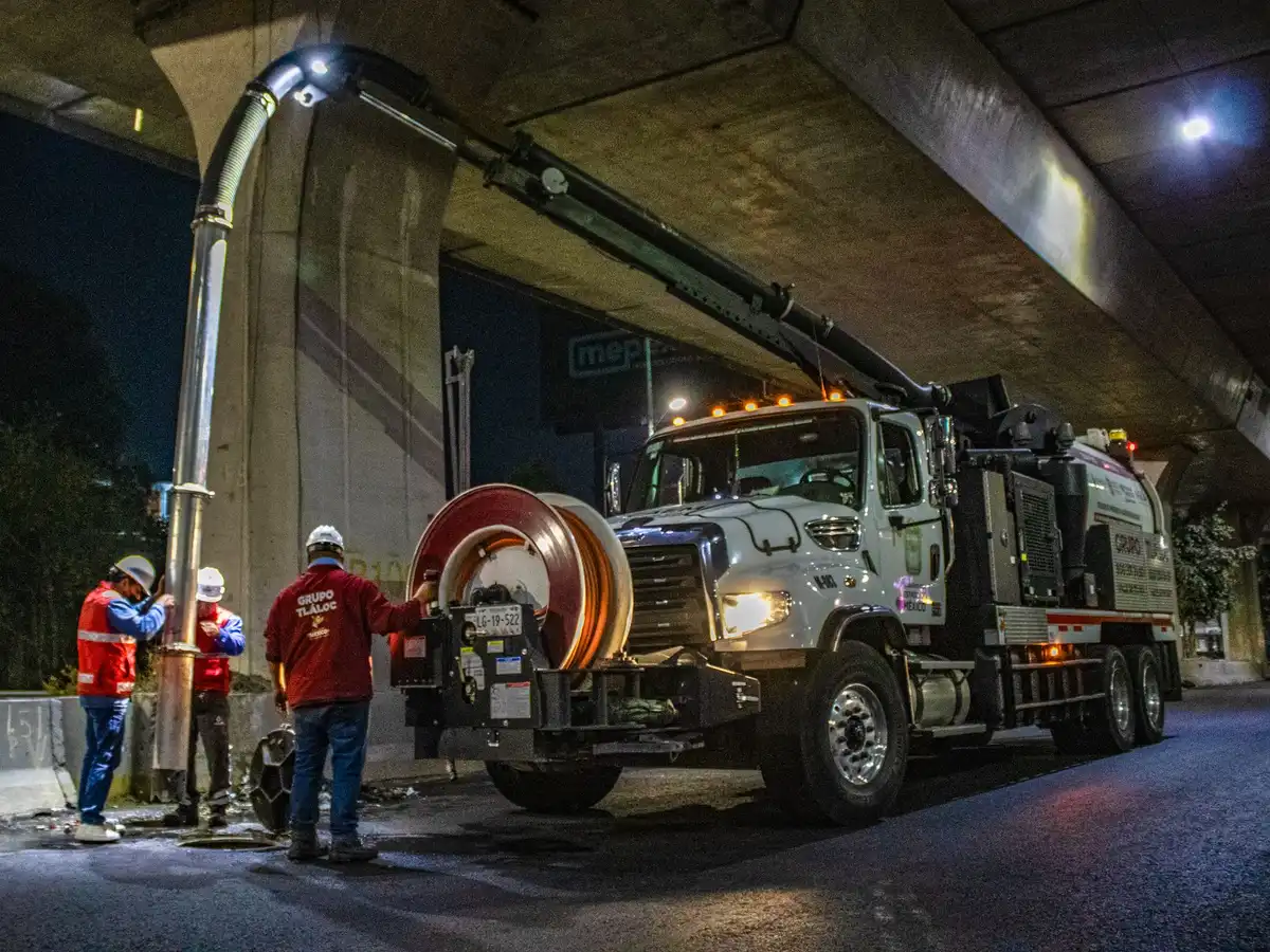 Equipe operando caminhão de vácuo em serviço de manutenção urbana durante a noite