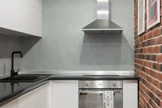 Cozinha contemporânea com parede de tijolos, eletrodomésticos de inox e coifa