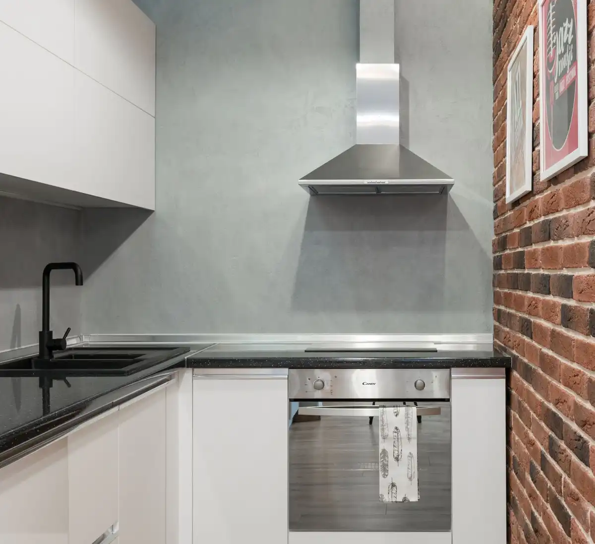 Cozinha contemporânea com parede de tijolos, eletrodomésticos de inox e coifa