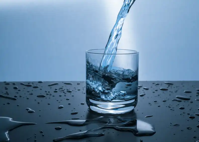 Água potável sendo servida em um copo de vidro transparente