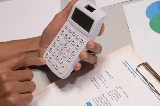 Pessoa usa calculadora ao lado de uma fatura