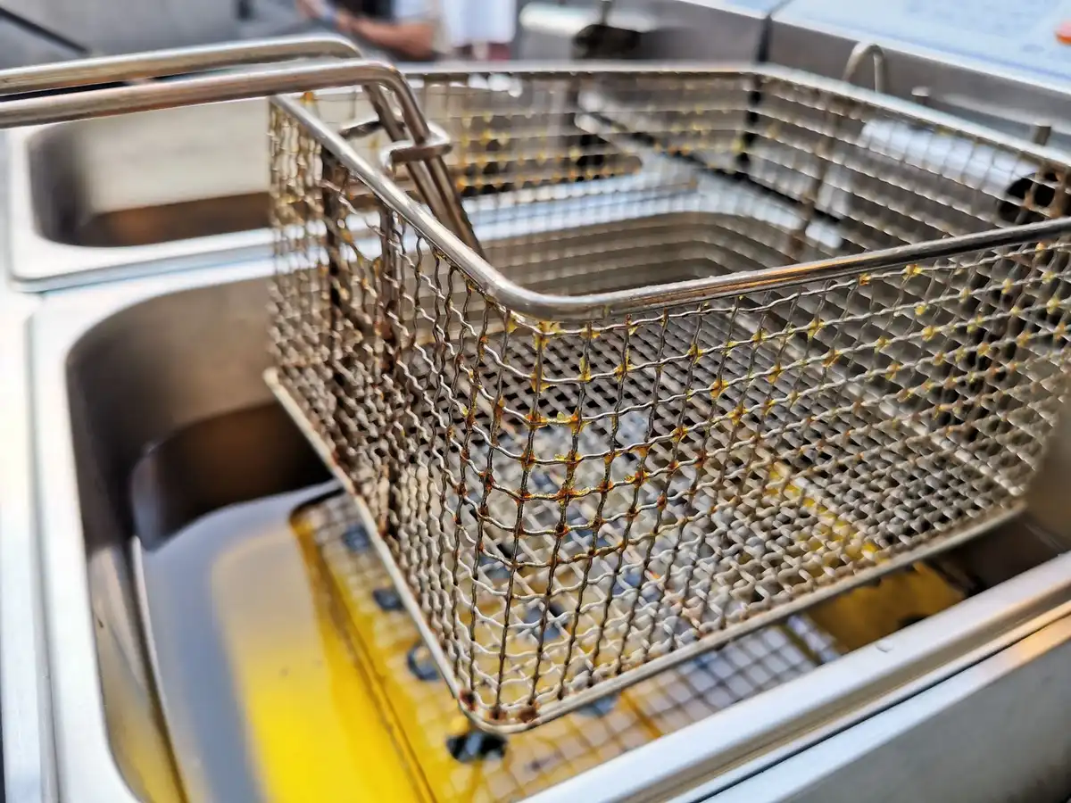 Cesto de fritadeira de inox sobre óleo quente