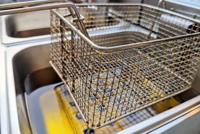 Cesto de fritadeira de inox sobre óleo quente